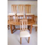 An oak dining table, with panelled top and extra leaf, and a set of six oak splat back dining