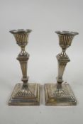 A pair of early C18th sterling silver waisted square column candlesticks, on weighted square