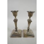 A pair of early C18th sterling silver waisted square column candlesticks, on weighted square