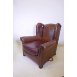 A brown leather wing back arm chair, with a vinyl seat cushion, 34" high