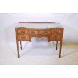 A C19th inlaid figured mahogany serpentine fronted kneehole desk of four drawers, raised on tapering