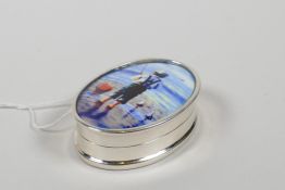 A sterling silver pill box decorated with a cold enamel plaque depicting a boy fishing, 1" x 1½"