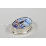 A sterling silver pill box decorated with a cold enamel plaque depicting a boy fishing, 1" x 1½"