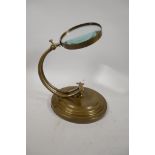 A brass desk top magnifying glass, 9" high, lens 5" diameter