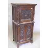 An oak cabinet with fall front over two cupboard doors, the panels carved with Gothic tracery, the