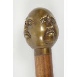 A hardwood walking stick with brass four face Buddha handle, 36" long