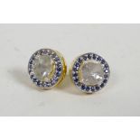A pair of silver gilt ear studs set with mine cut diamonds encircled by sapphires