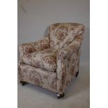 A 1930s scroll arm easy chair, raised on bun feet