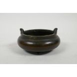 A Chinese squat form bronze censer with two handles, on tripod supports, 4½" diameter, impressed