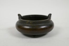 A Chinese squat form bronze censer with two handles, on tripod supports, 4½" diameter, impressed