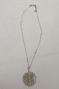 A fine white metal filigree pendant, set with a central diamond, surrounded by seed pearls and