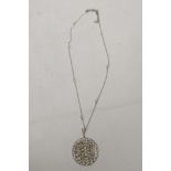 A fine white metal filigree pendant, set with a central diamond, surrounded by seed pearls and