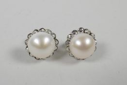 A pair of silver and pearl stud earrings encircled by cubic zirconia