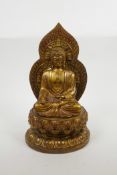 A Chinese metal figure of Buddha seated on a lotus throne with gilt and coppered patina, four