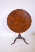 A Georgian mahogany tilt top occasional table with single piece dished top, raised on a turned