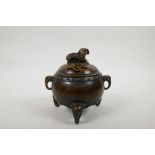A Chinese bronze barrel shaped censer with two elephant mask handles and elephant knop, raised on