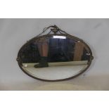 A brass oval wall mirror with urn decoration to top, 31" x 24"