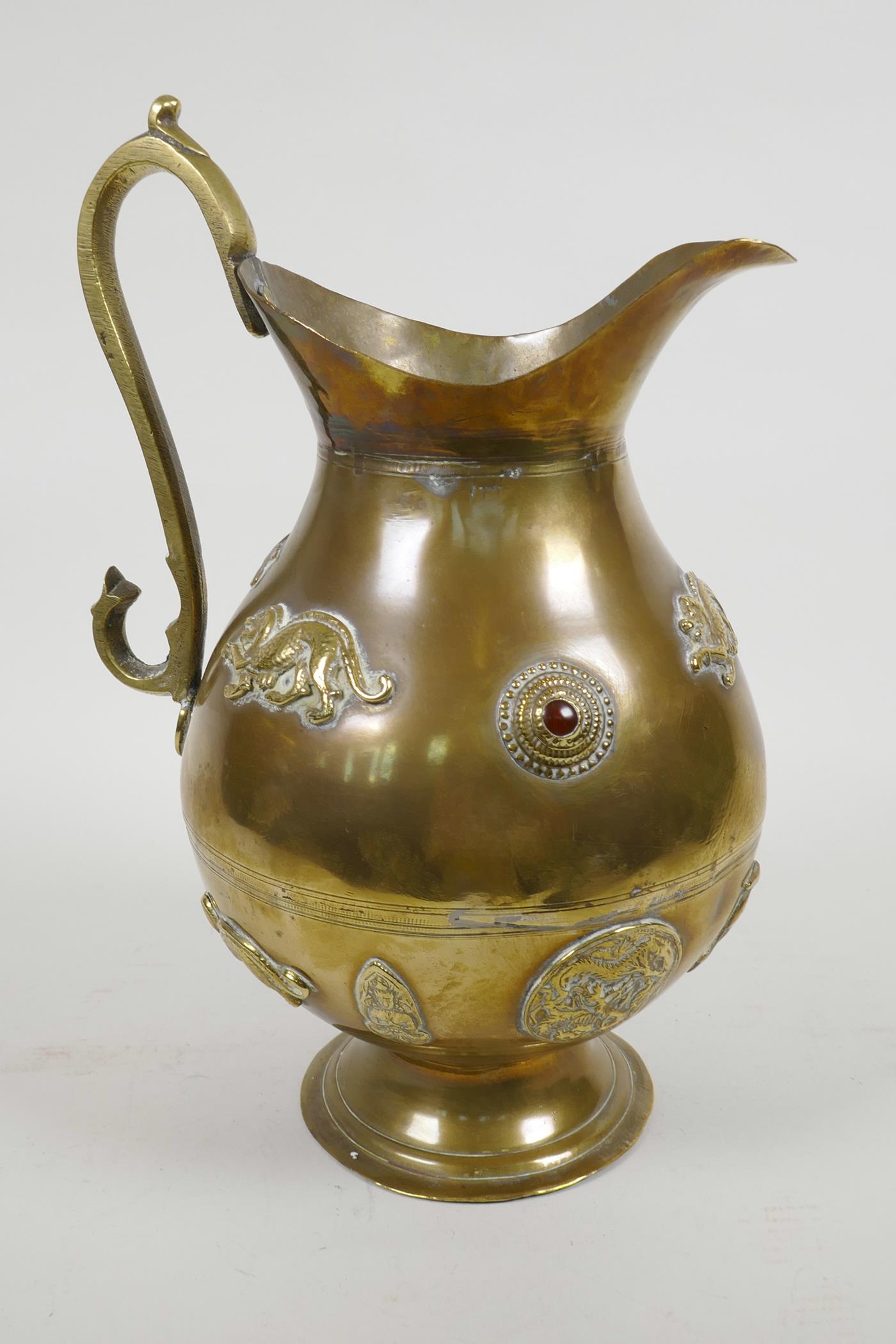 A heavy oriental bronze ewer set with applied cabochon gemstones and plaques of exotic animals and a