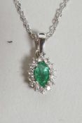 An 18ct white gold, emerald and diamond cluster pendant necklace on a gold chain