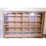 An early C20th large pine open bookcase with glazed sliding doors and bracket feet, 85" x 14", 58"