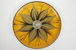 A studio pottery wall plate decorated with a flower, signed, 10½"diameter