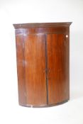 A Georgian mahogany bowfronted hanging corner cupboard with inlaid frieze and boxwood stringing