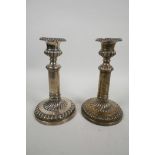 A pair of silver Regency candlesticks, with plain round bases, all with hand chased, melon fluted