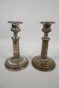 A pair of silver Regency candlesticks, with plain round bases, all with hand chased, melon fluted