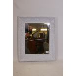 A wood framed mirror with scrolled mouldings and chalky white paint finish, 24" x 20"