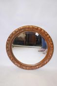 A large circular wall mirror, with moulded decorative scrolling frame and copper/bronze paint