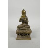 A Tibetan gilt bronze of Buddha on a pierced stand, impressed marks verso, 5" high