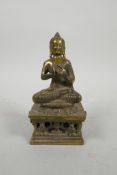 A Tibetan gilt bronze of Buddha on a pierced stand, impressed marks verso, 5" high