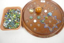 A large wooden solitaire board, A/F, together with a quantity of vintage marbles