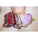 A piano accordion in case, with lesson books
