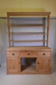 A C19th pitch pine dresser, with delft rack over three drawers and two cupboards flanking an open