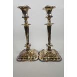 A pair of classical style Sheffield plated candlesticks, with cast floral decoration on shaped
