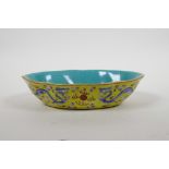 A Chinese porcelain dish with blue and pink enamel dragon decoration on a yellow field, four