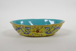 A Chinese porcelain dish with blue and pink enamel dragon decoration on a yellow field, four