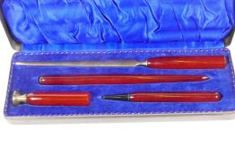 A metal cased desk writing set of paper knife, pen, pencil and seal with composition handles