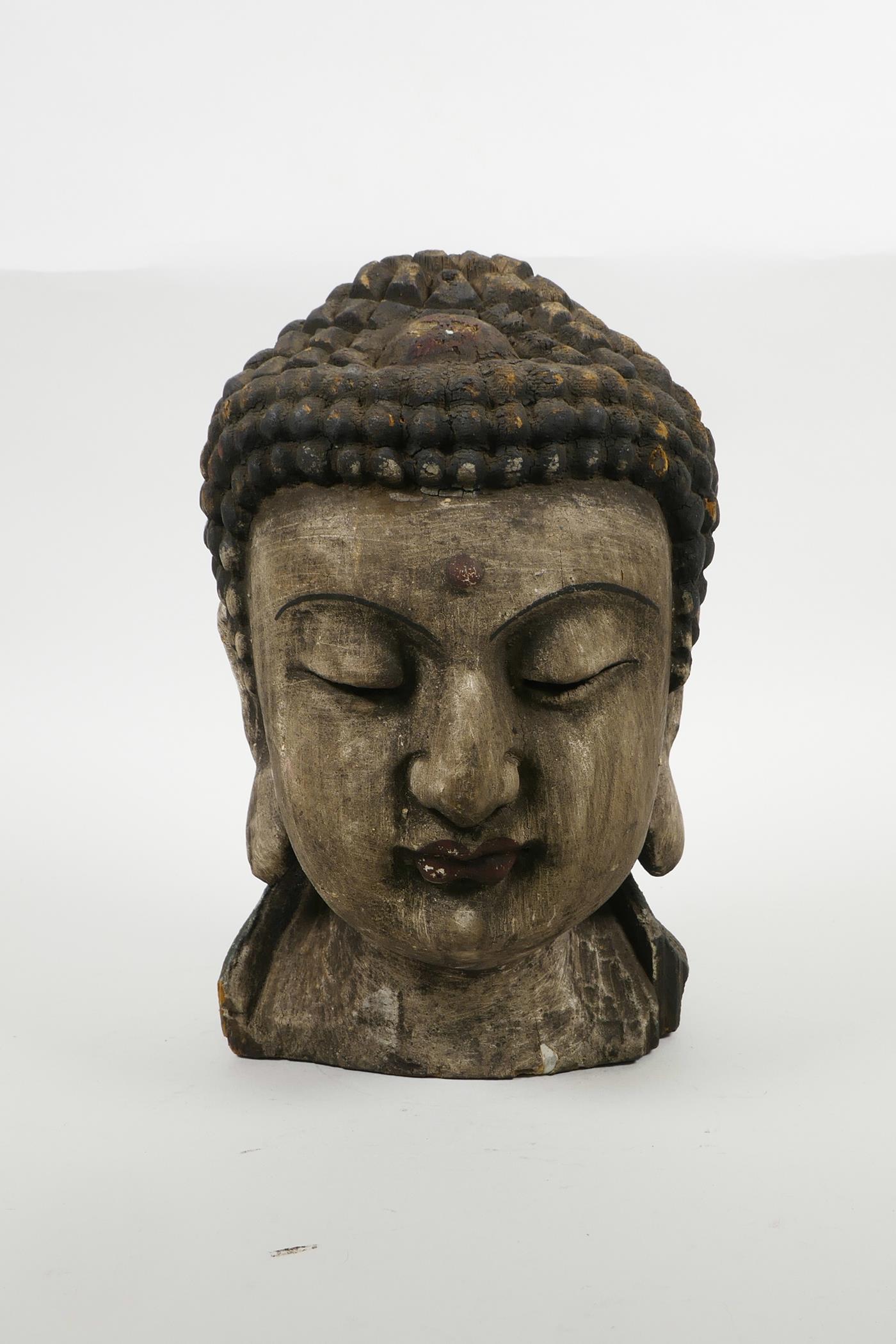 An oriental carved and painted Buddha head, 9½" high