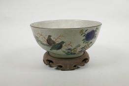 A Chinese crackleware bowl with famille verte decoration of birds in a landscape, on a carved