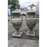 A pair of large concrete garden urns and covers with classical style decoration, breaks down into