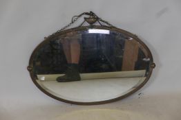 A brass oval wall mirror with urn decoration to top, 31" x 24"