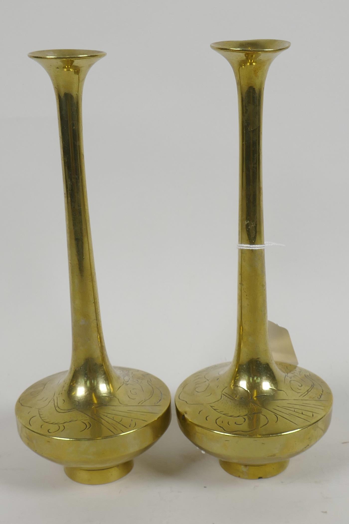 A pair of Chinese brass long necked specimen vases having engraved decoration of dragons, 8½" high