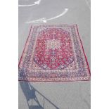A large Persian red ground Isfahan carpet with traditional floral medallion design, 118" x 147"