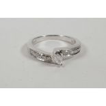 A 9ct white gold ring set with a central marcasite cut diamond and diamond channel shoulders,