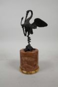 A bronzed metal figure of a crane standing on a tortoise entwined by a snake, on a marbled stone