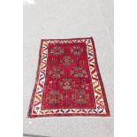 An Iranian deep pile red ground village rug with an unique Bokhara design and unusual motifs, 60"
