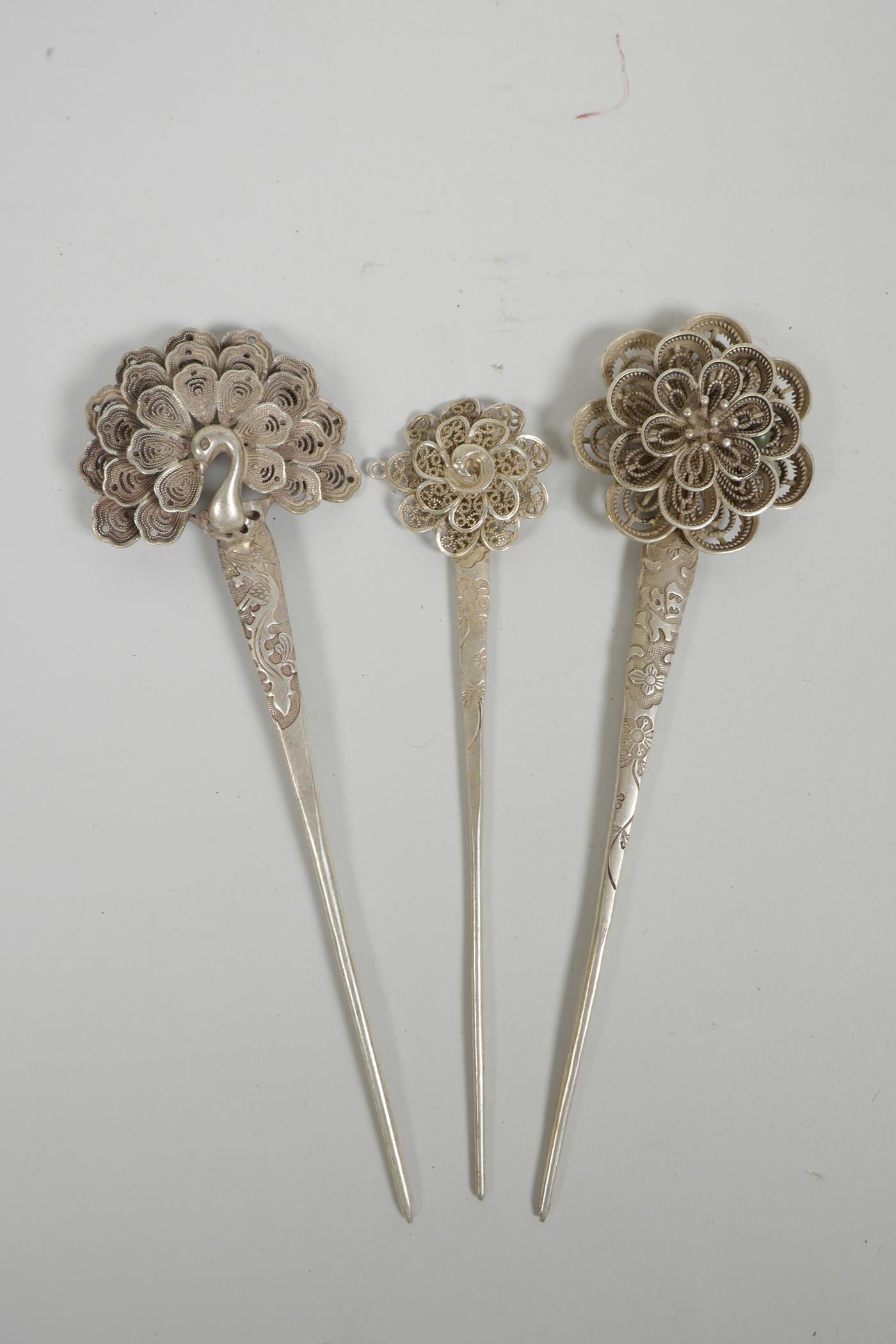Three Chinese silvered metal hairpins with floral and peacock decoration, impressed character marks,