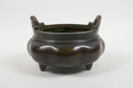 A Chinese bronze two handled censer of lobed form, raised on tripod feet, impressed 6 character mark
